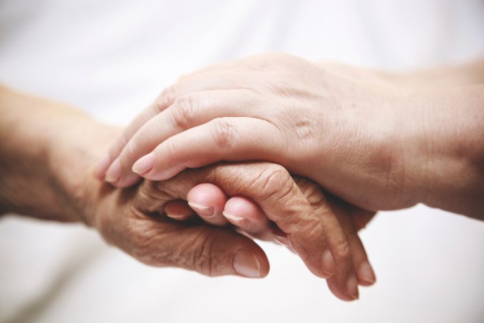 adult helping senior in hospital