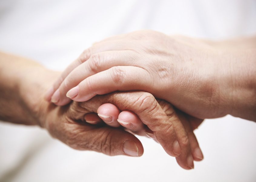 adult helping senior in hospital